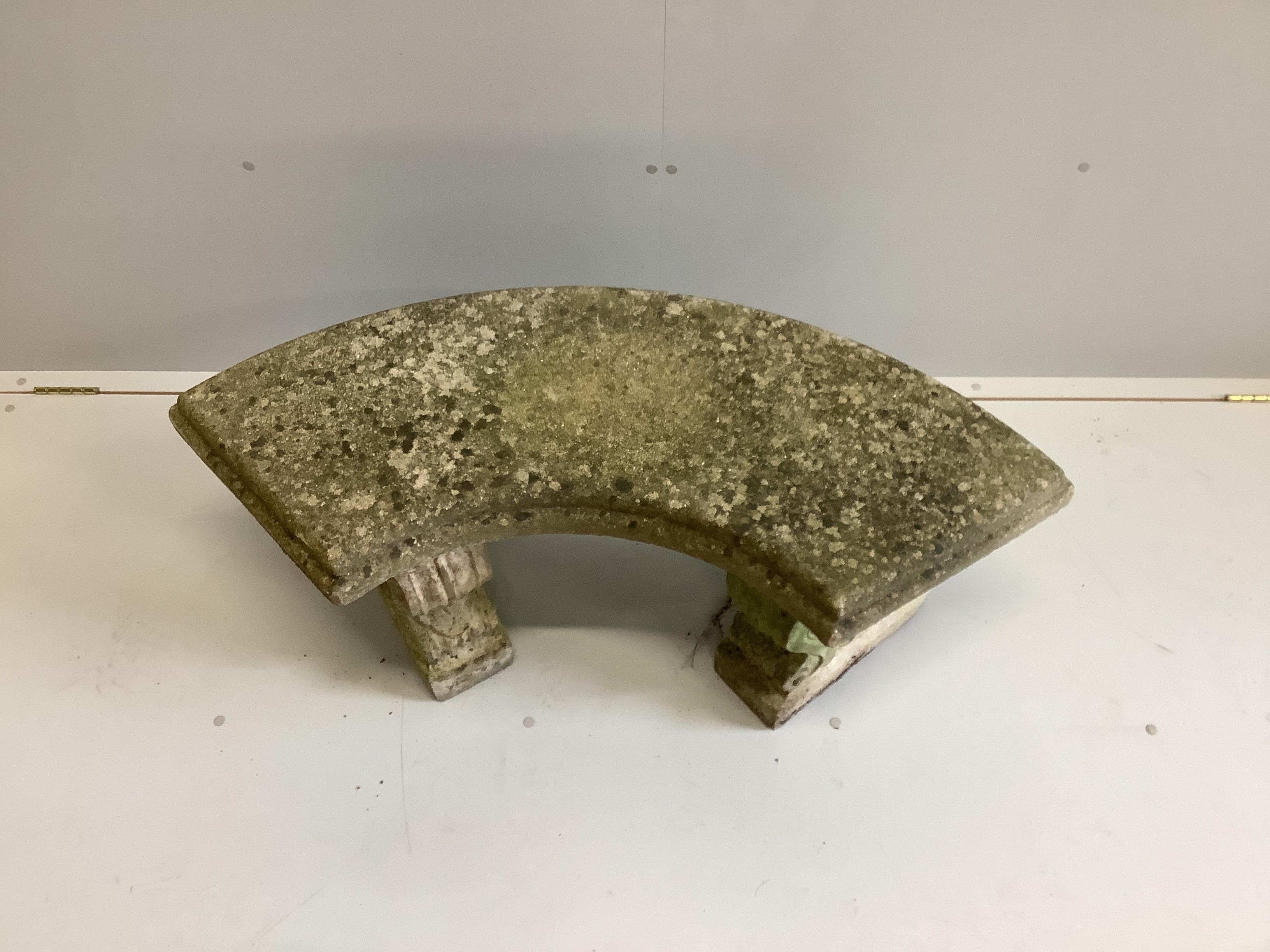 A weathered reconstituted stone curved garden bench, width 110cm, depth 48cm, height 45cm